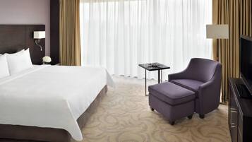 A hotel room with a large bed, a small table, a chair, and a television.