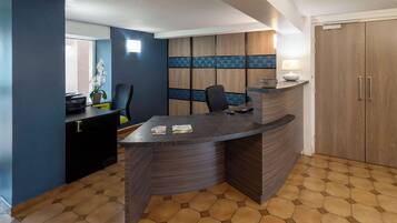 Un espace d’accueil moderne avec un comptoir incurvé, un coin salon et une grande armoire en bois.