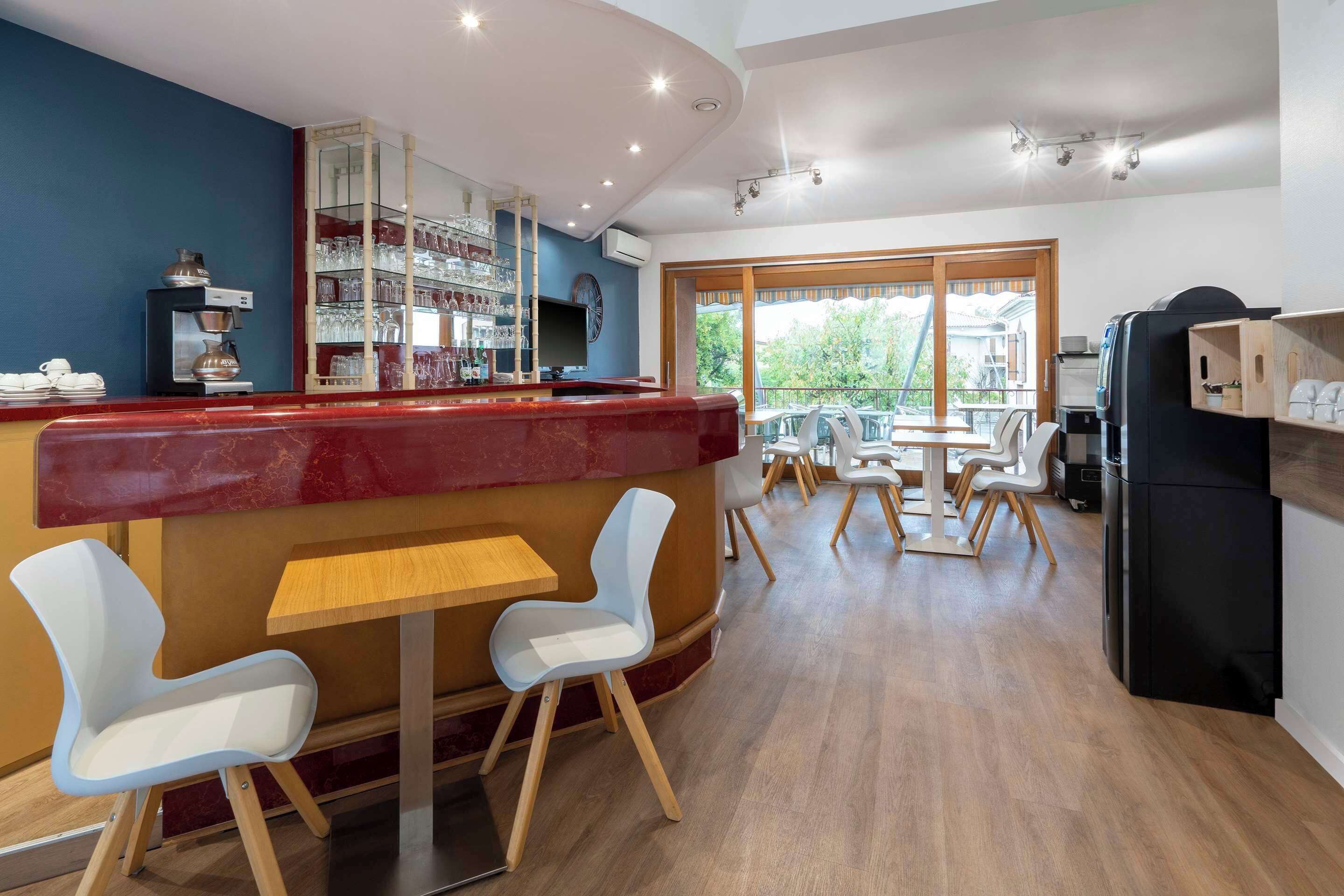 A modern restaurant with a bar area, seating, and a view of the outdoors.