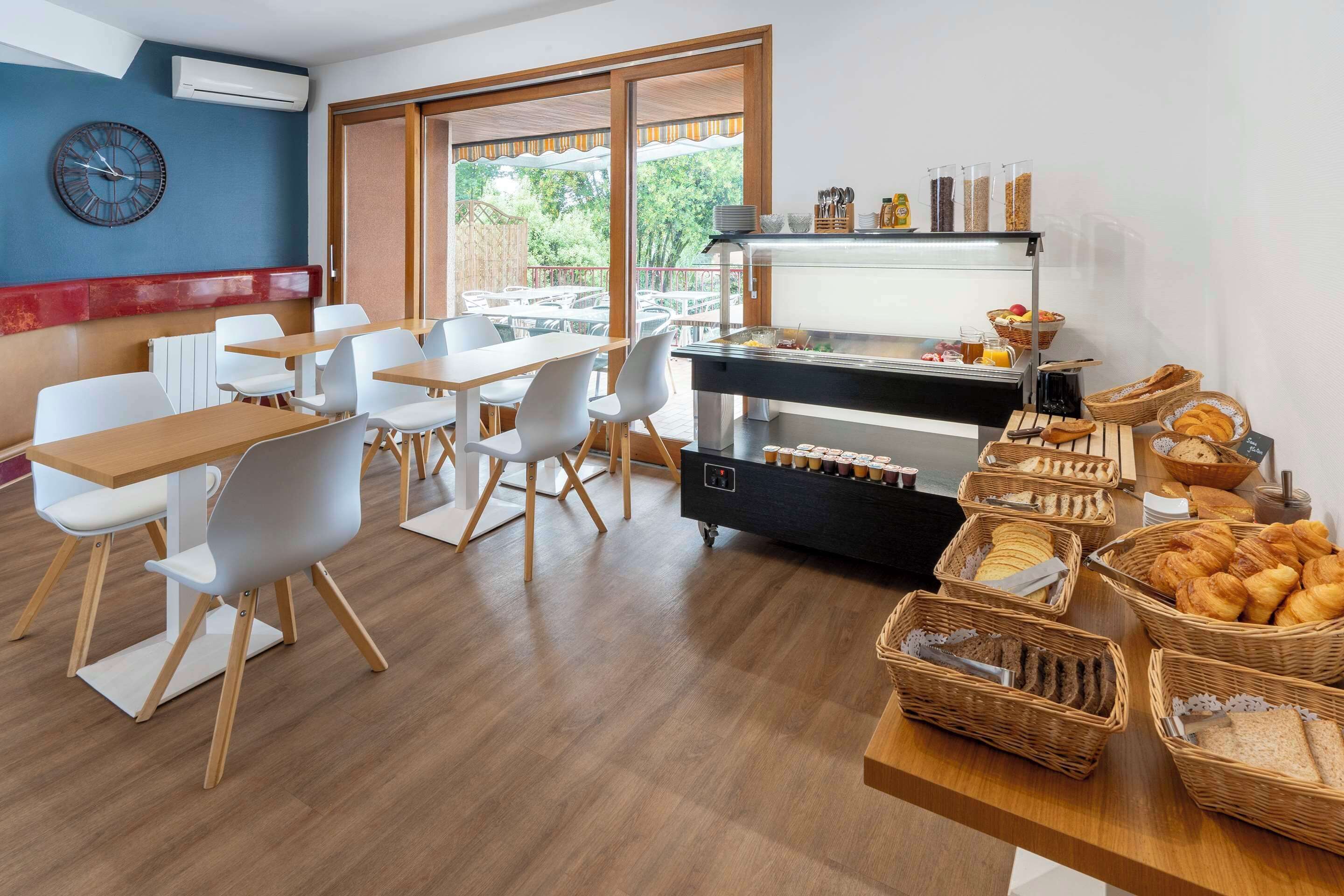 Een ontbijtruimte met tafels, stoelen en een buffet met diverse etenswaren.