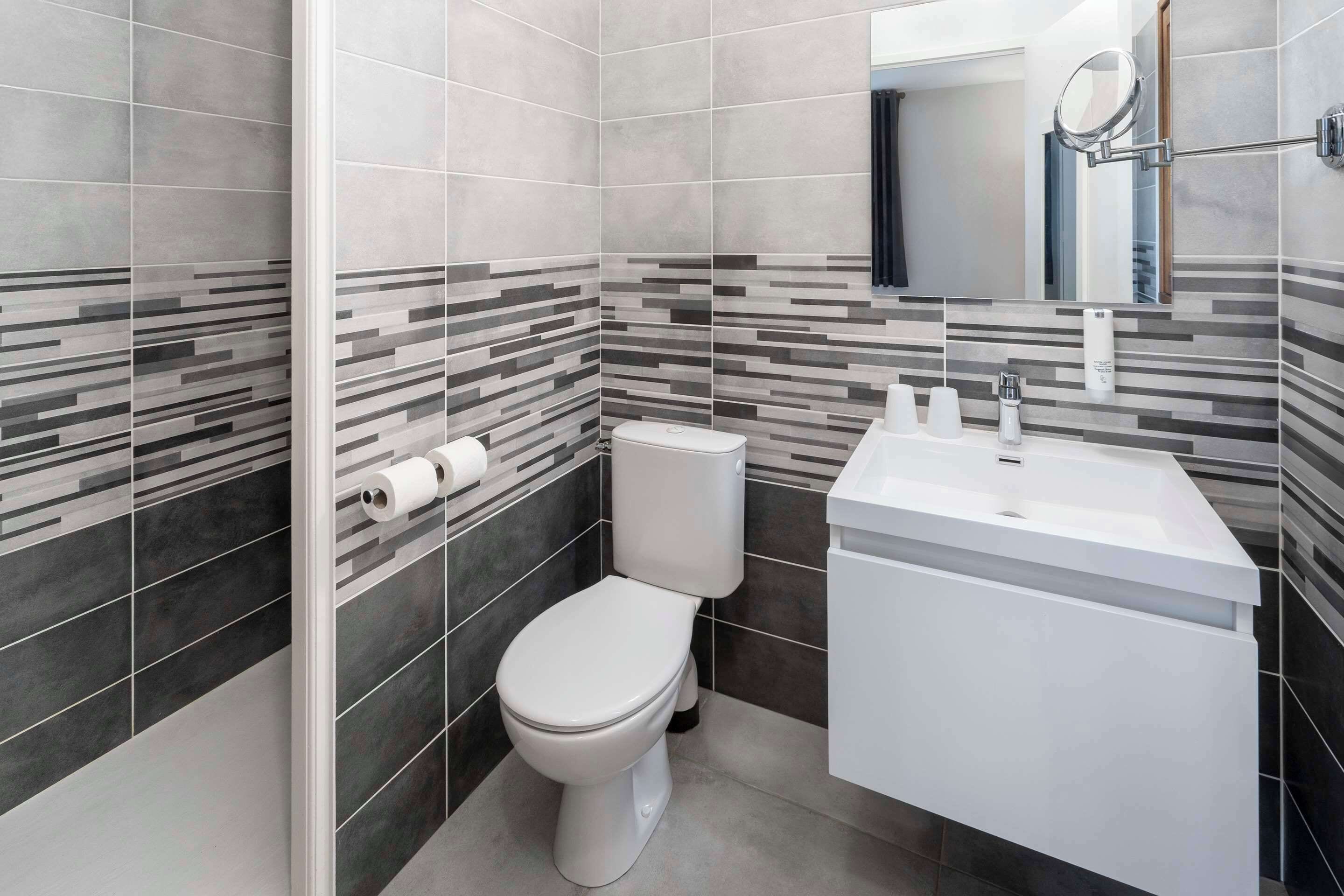 Une salle de bain moderne avec des toilettes, un lavabo et un miroir.