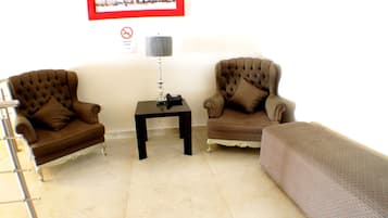 A living room with two brown armchairs, a small table with a lamp, and a framed picture on the wall.