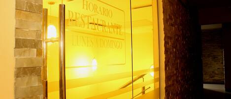A glass door with the text "HORARIO RESTAURANTE LUNES A DOMINGO" indicating a restaurant's operating hours.