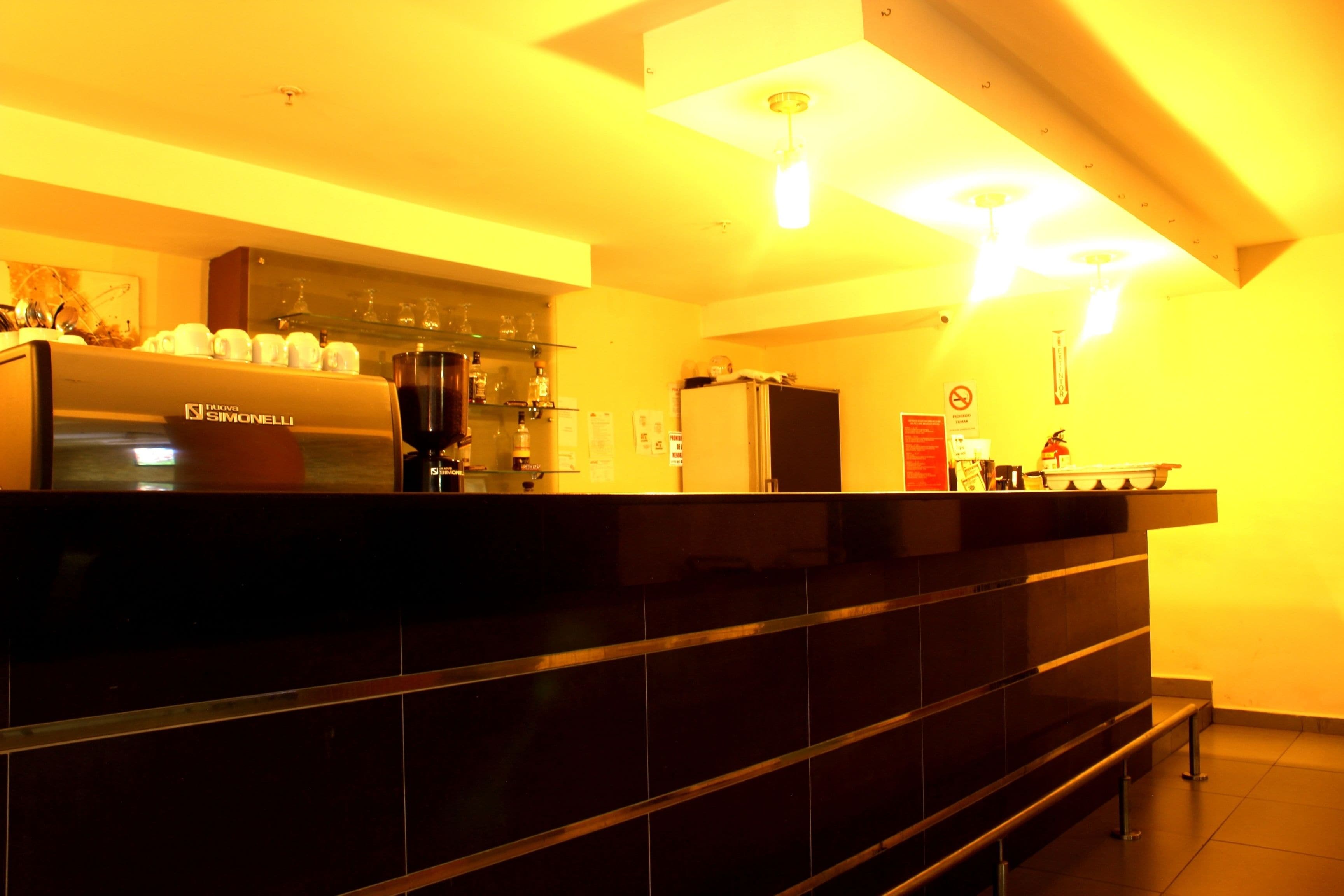 A modern kitchen with a Simonelli espresso machine, a refrigerator, and a glass display case.