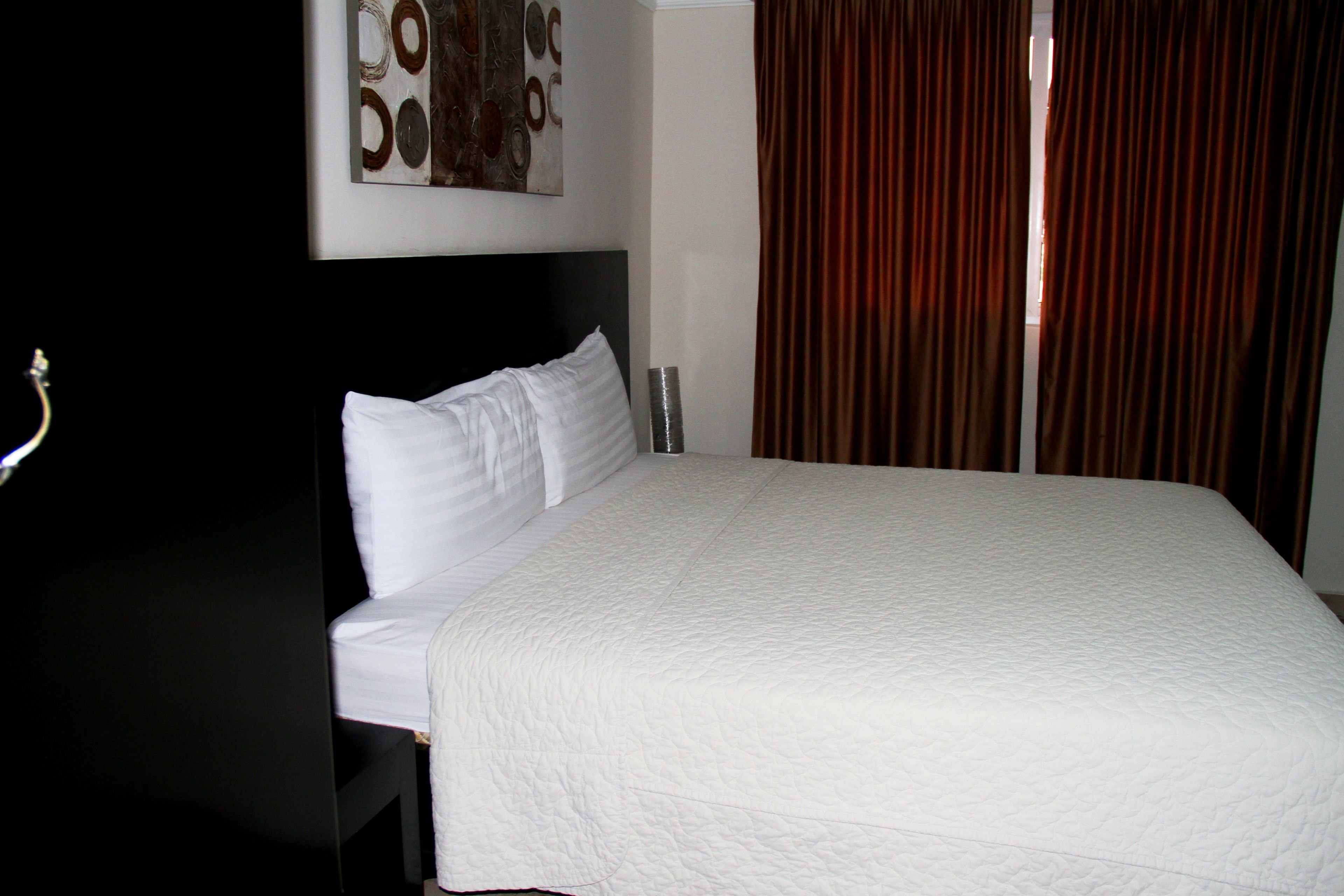 A neatly made bed with white bedding in a hotel room.