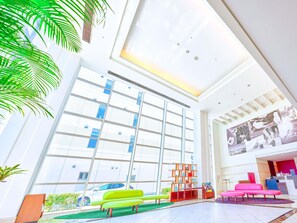 Un moderno vestíbulo de hotel con amplios ventanales, un mostrador de recepción y zonas de estar.
