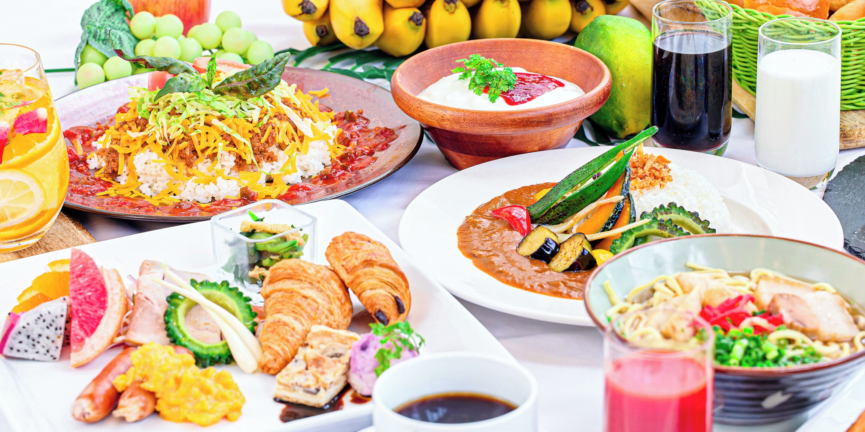 A table with various dishes including rice, meat, vegetables, and pastries, along with drinks and fruits.