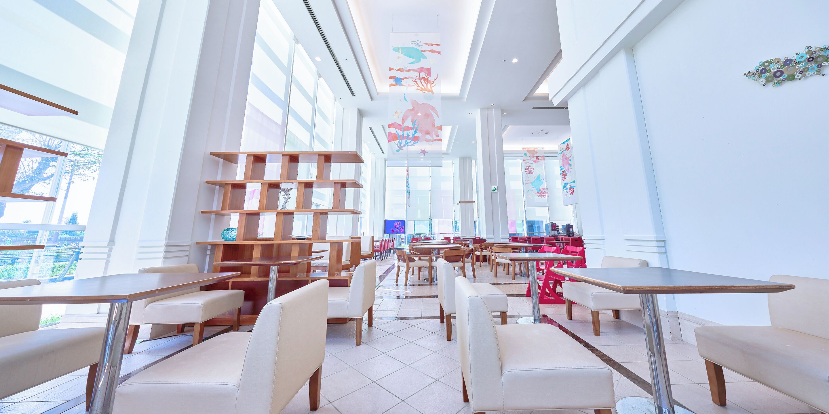 A spacious indoor dining area with high ceilings, large windows, and modern furniture.