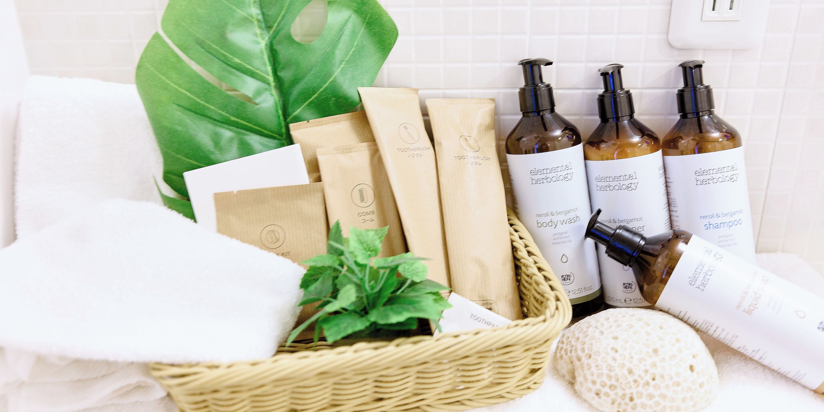 A bathroom with a white towel, a green plant, and toiletries including body wash and shampoo.