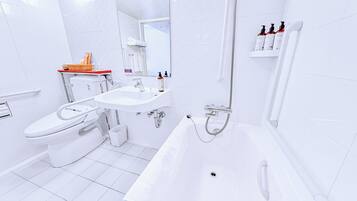 A modern bathroom with a toilet, sink, and bathtub.