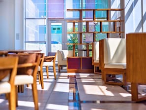 A modern interior with wooden furniture, a glass door entrance, and a view of greenery outside.