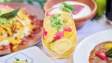 Una mesa de comedor con varios platos, incluyendo un vaso de bebida helada con rodajas de fruta y menta, y un tazón de sopa.