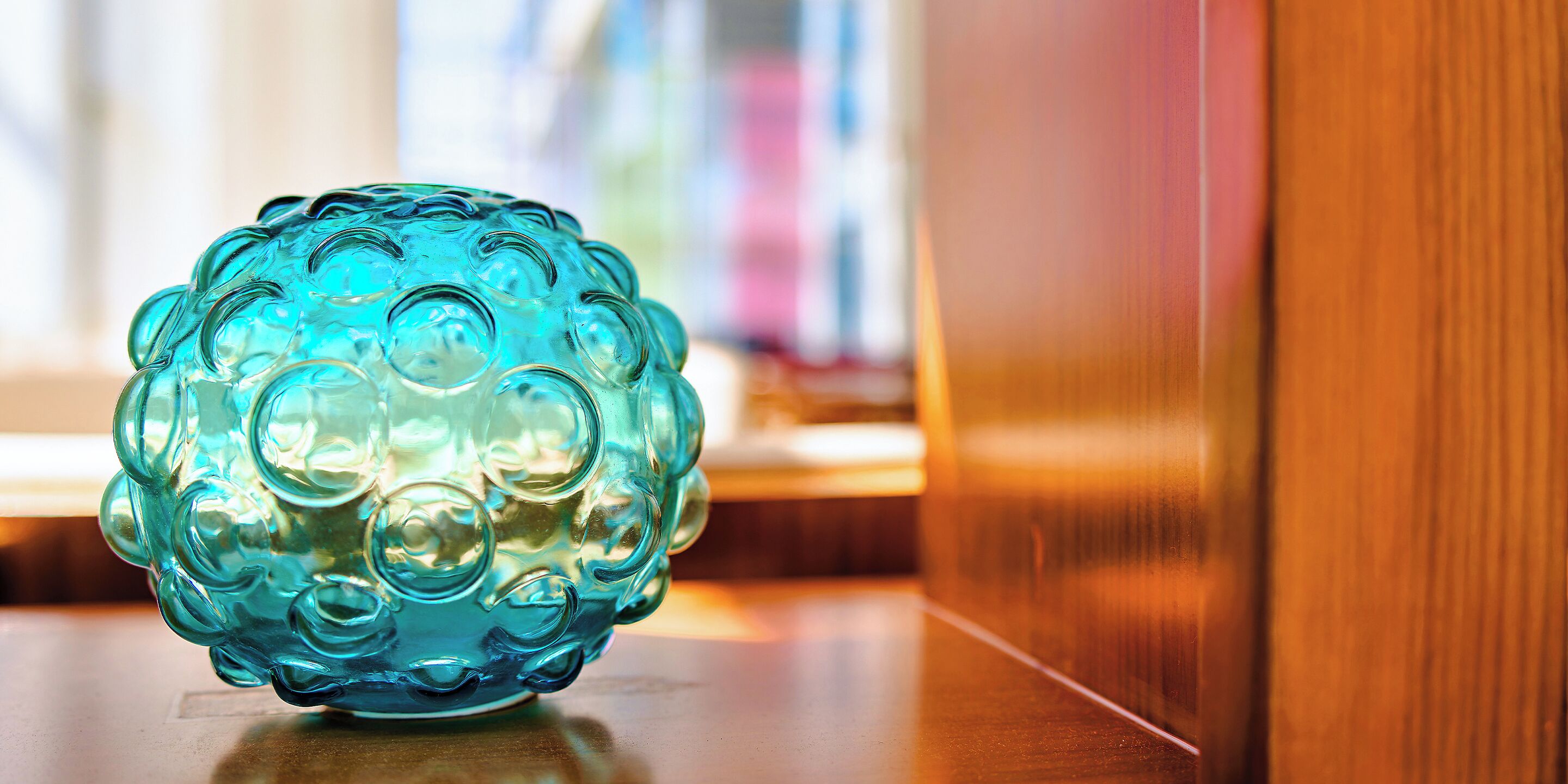 A blue glass object on a wooden surface.