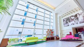 A spacious lobby with large windows, a reception desk, and modern seating areas.