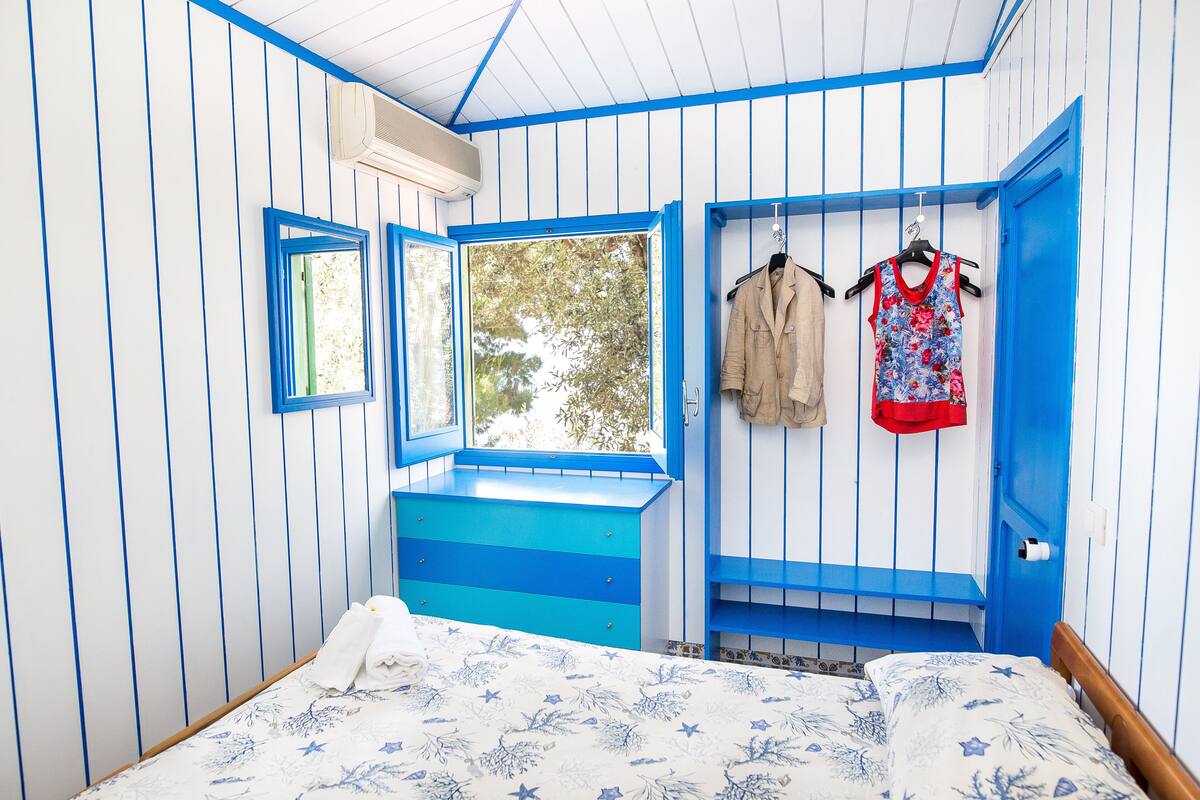 Une pièce avec un lit, une fenêtre et une porte bleue.
