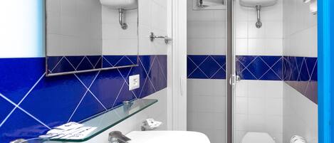 A bathroom with a white sink, glass shelf, and a toilet.