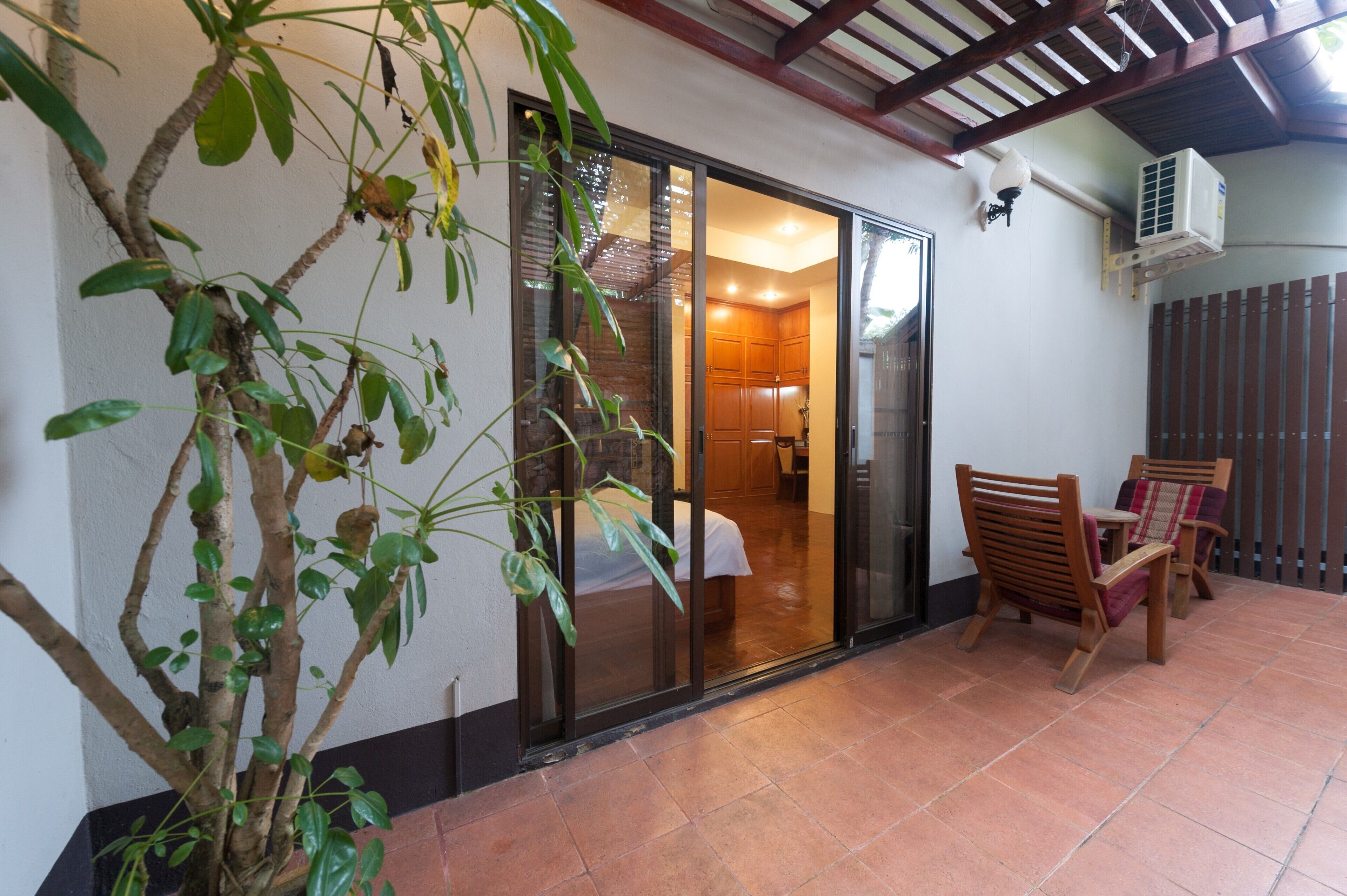 A room with a sliding glass door leading to a bathroom, a wooden chair, and a potted plant.