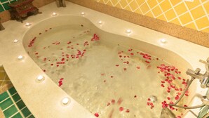 A bathtub with rose petals and candles. - Ruen Ariya Resort (Mae Rim)