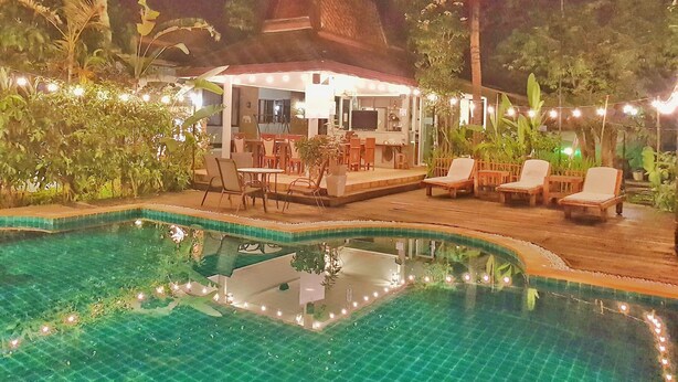 A pool area with lounge chairs and a covered seating area, surrounded by greenery. - Ruen Ariya Resort (Mae Rim)