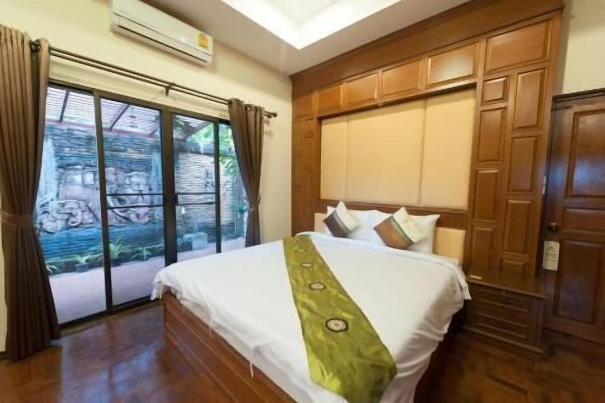 A bedroom with a bed, wooden headboard, and a view through a window.