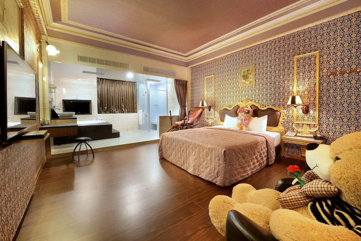 Camera d'albergo con un letto grande, una scrivania, una televisione e uno specchio.