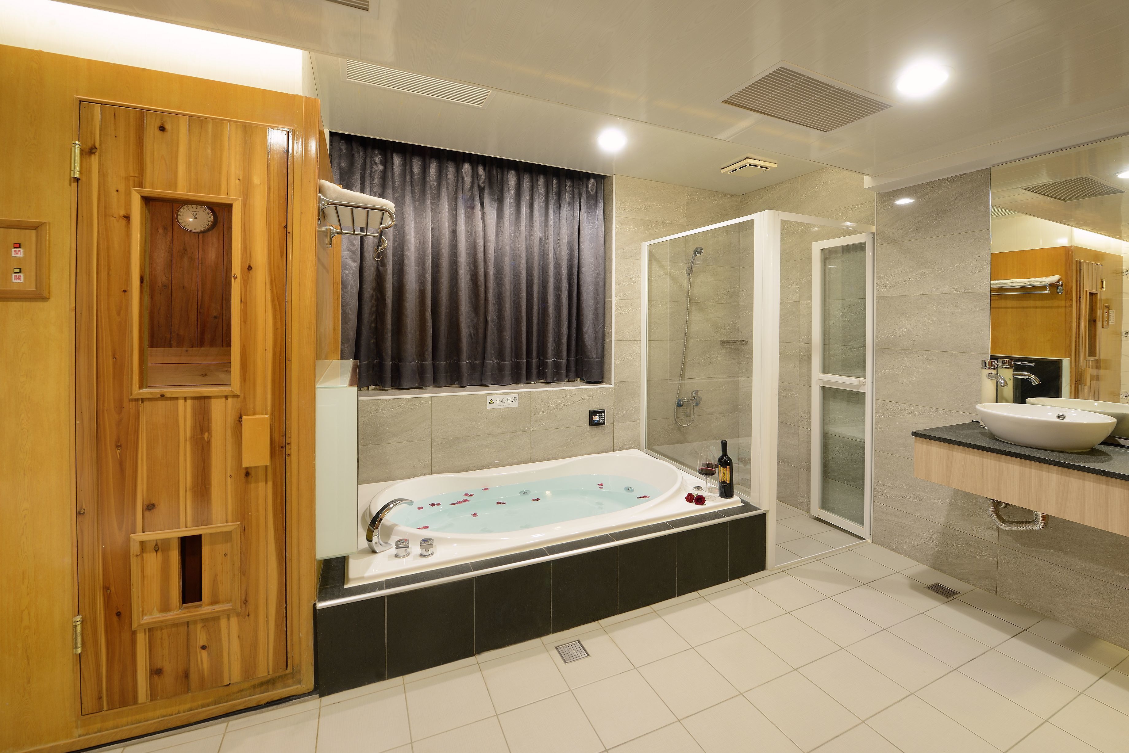 A modern bathroom with a wooden sauna door, a freestanding bathtub, a glass-enclosed shower, and a vanity with a sink.