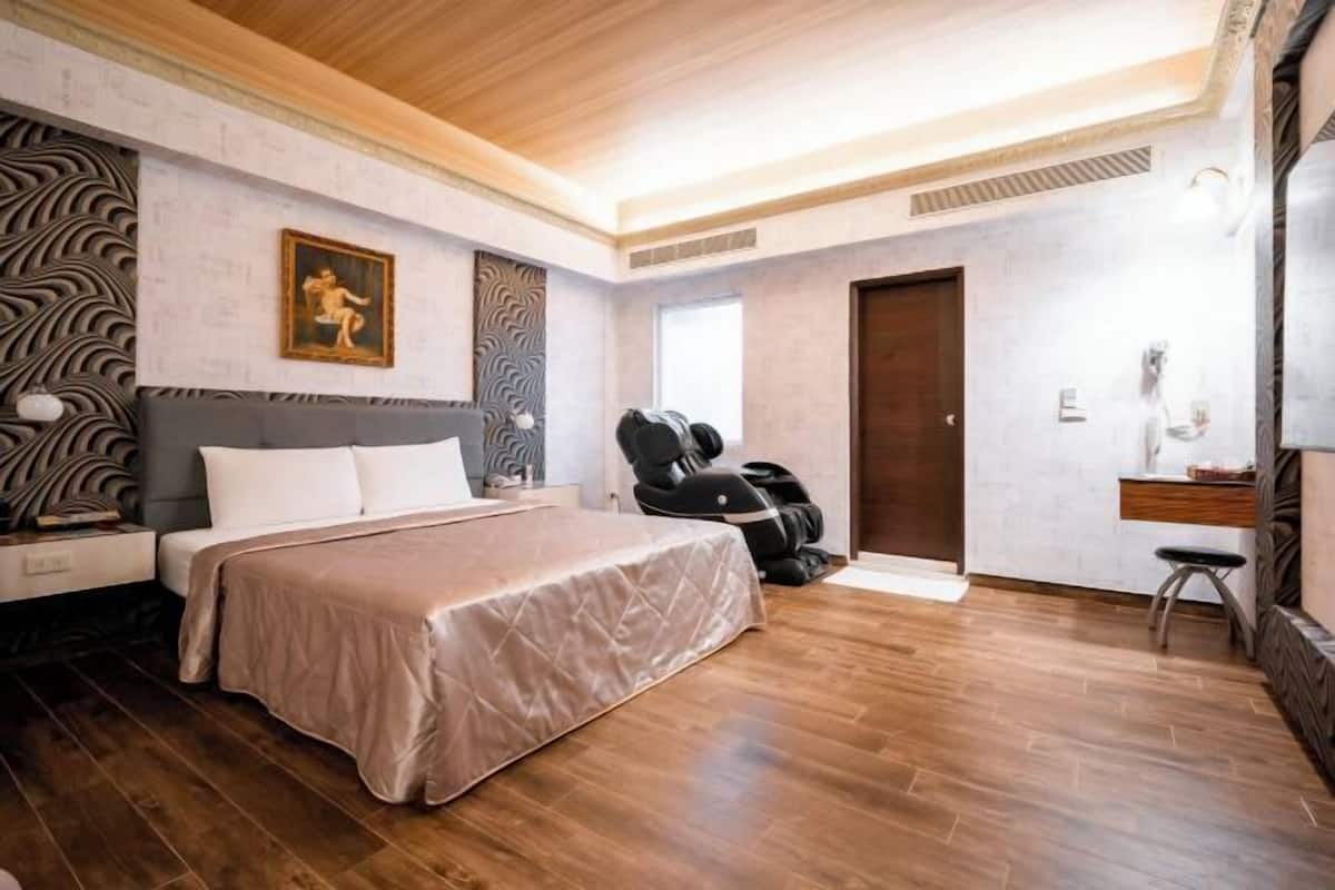 Camera da letto moderna con un letto, poltrona massaggiante e soffitto in legno.