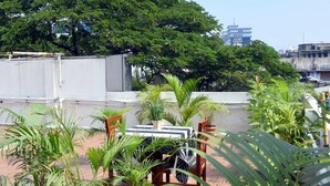A rooftop terrace with potted plants, a table, and chairs. - Hotel Pearl International (Chennai)