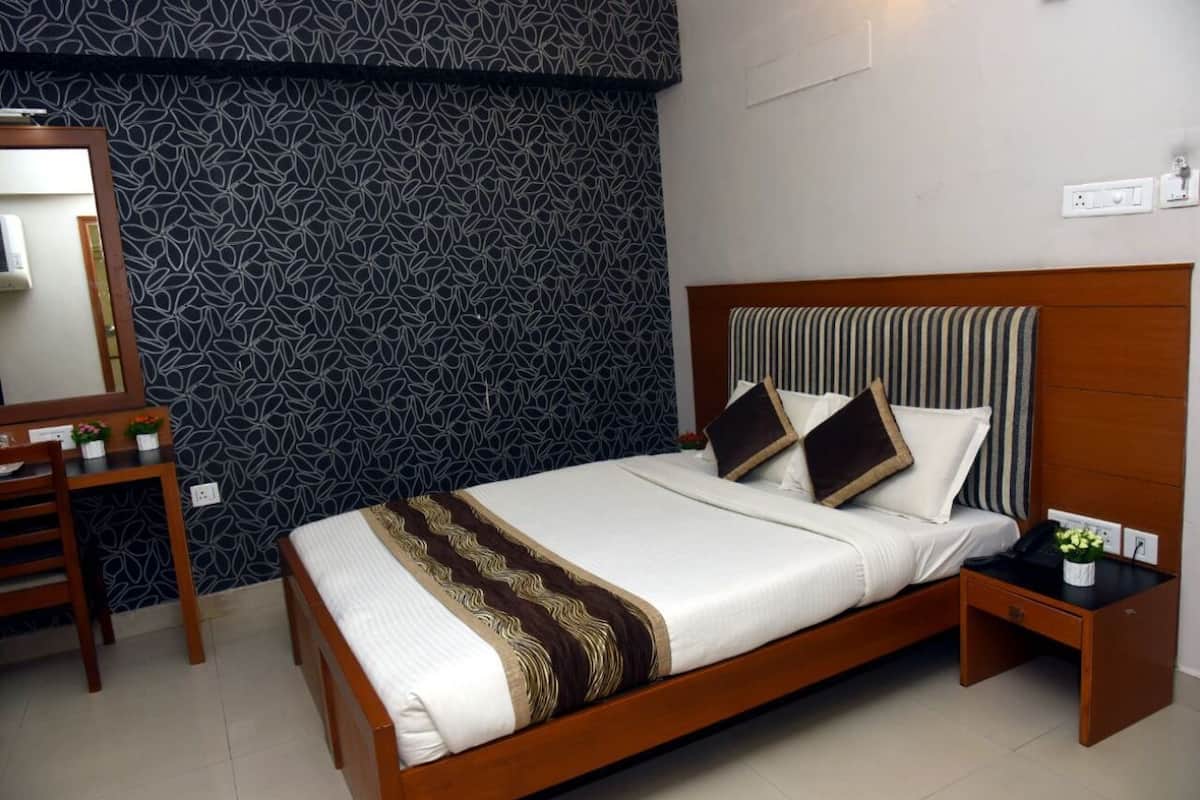 A neatly made bed with a striped headboard, a bedside table with a lamp, and a mirror on the wall.