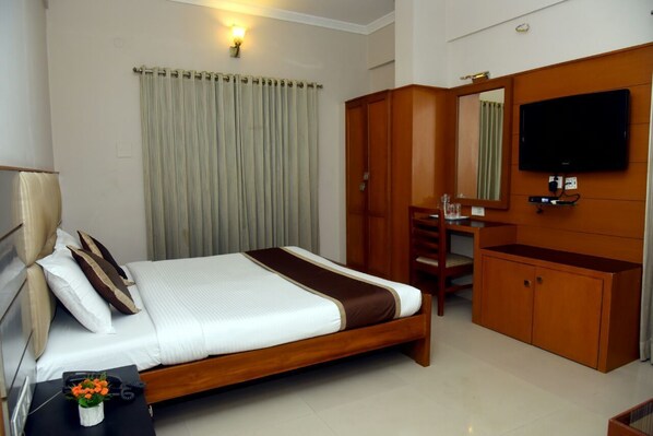 A hotel room with a bed, a desk, a TV, and a wardrobe.