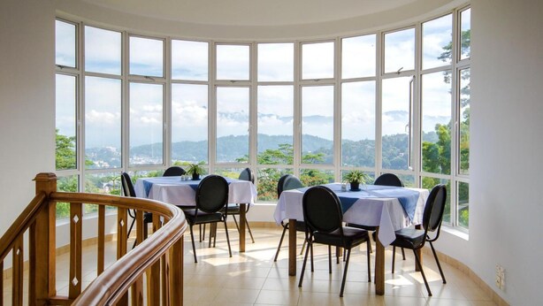 Un comedor con varias mesas y sillas, ventanas amplias que ofrecen vistas del paisaje.