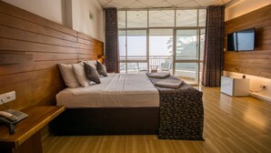 Un dormitorio moderno con una cama grande, cabecera de madera, un televisor de pantalla plana en la pared y un balcón con vistas.