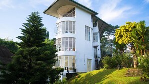 Un edificio de varios pisos con fachada blanca, múltiples balcones y ventanas grandes.