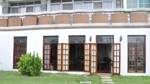 Un edificio de dos pisos con fachada blanca y varias ventanas.