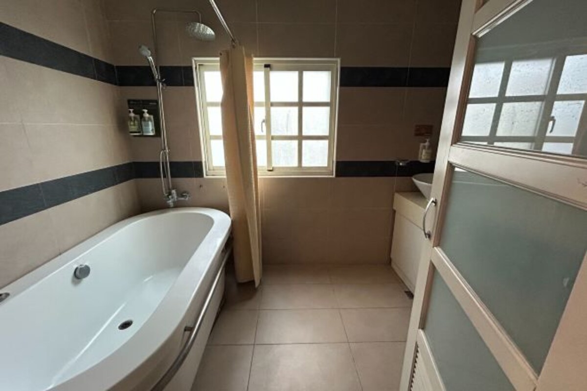 A bathroom with a bathtub, a window, and a shower.