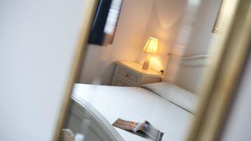 A hotel room with a bed, a nightstand, a lamp, and a magazine on the bed.