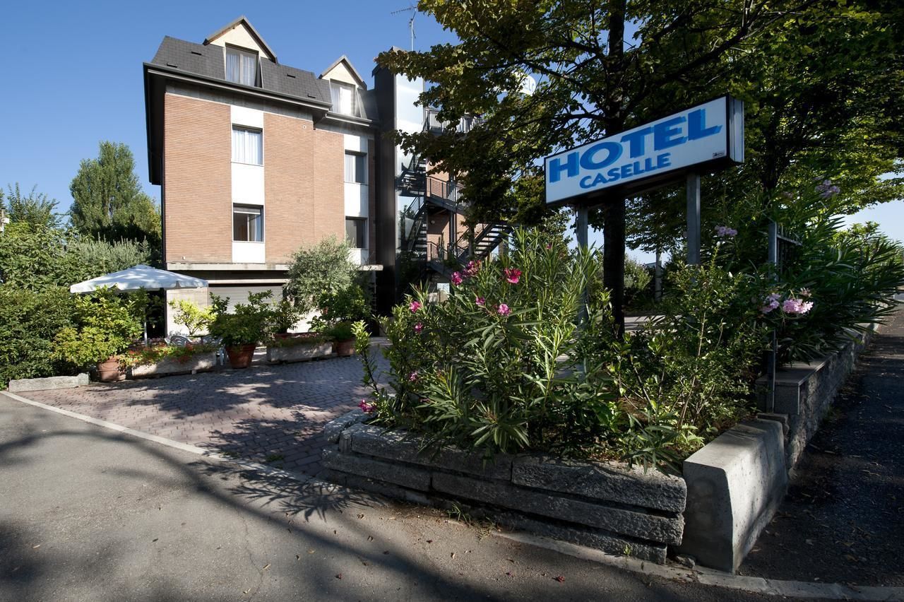 A hotel sign with "HOTEL CASSELLE" written on it, surrounded by greenery and a paved driveway.