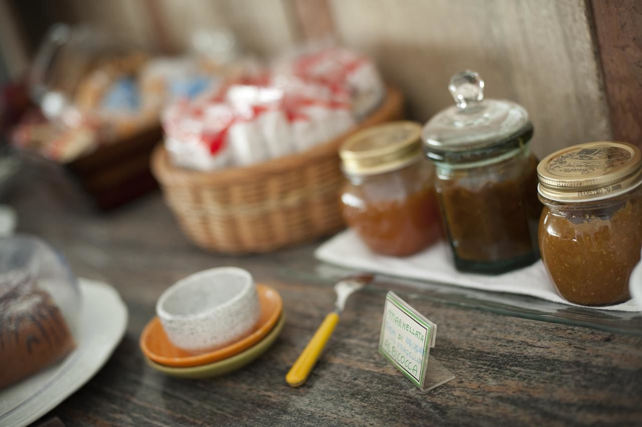 A rustic wooden table with jars of preserves, a basket of bread, and a small sign indicating the type of preserves.