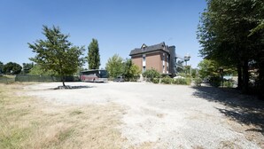 Un espace de stationnement avec une surface en gravier, un autobus et un bâtiment en arrière-plan.