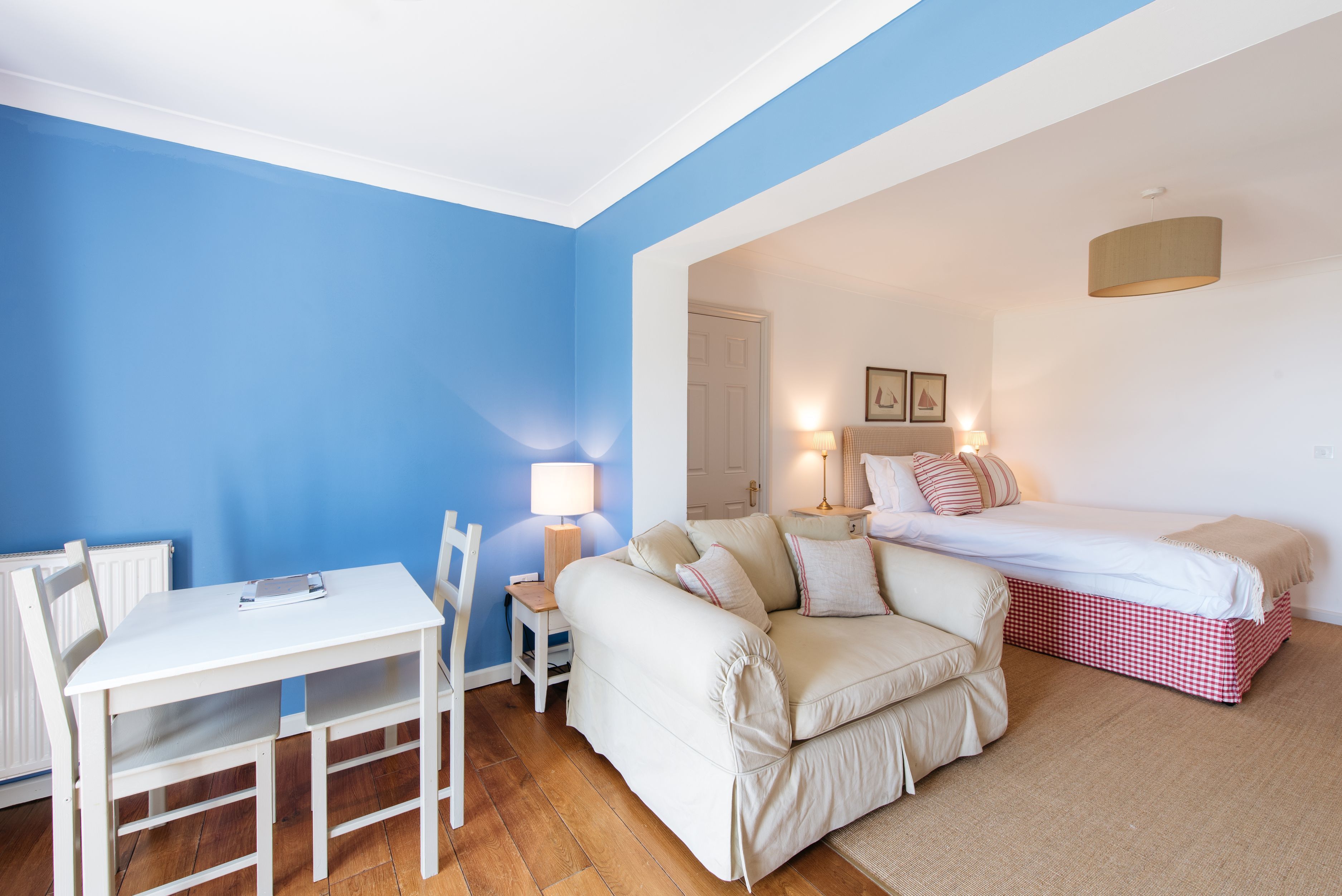 Un dormitorio con cama, mesita de noche, lámpara y silla.
