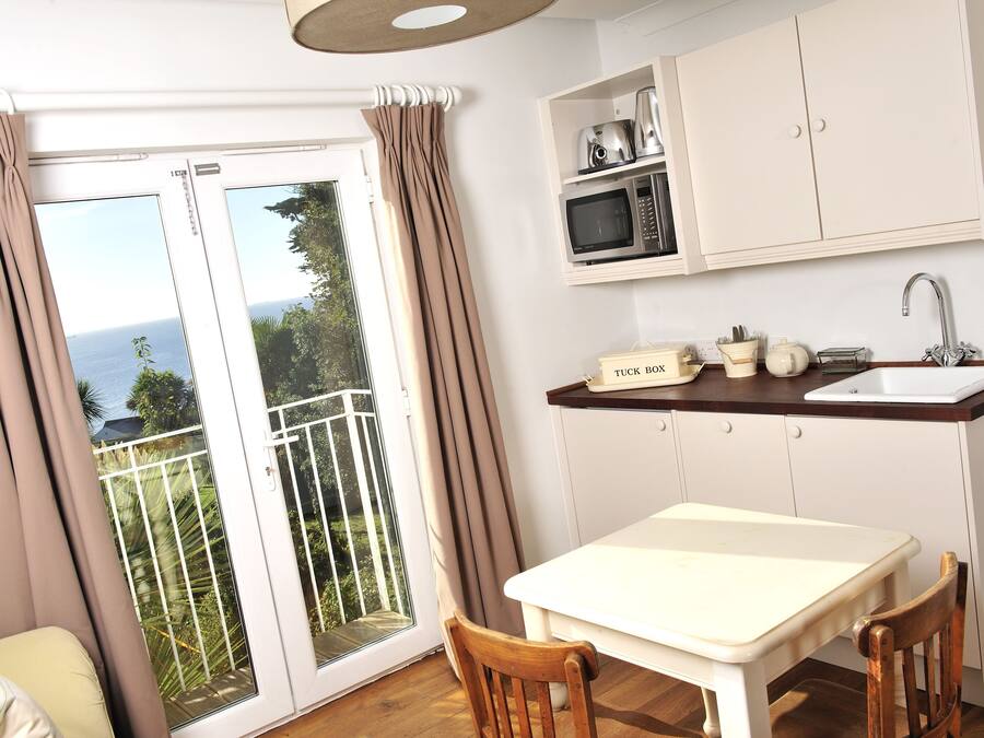 A compact kitchen with a dining area, a sink, and a microwave.