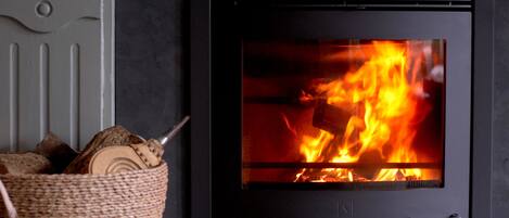 A fireplace with visible logs and a basket of firewood.