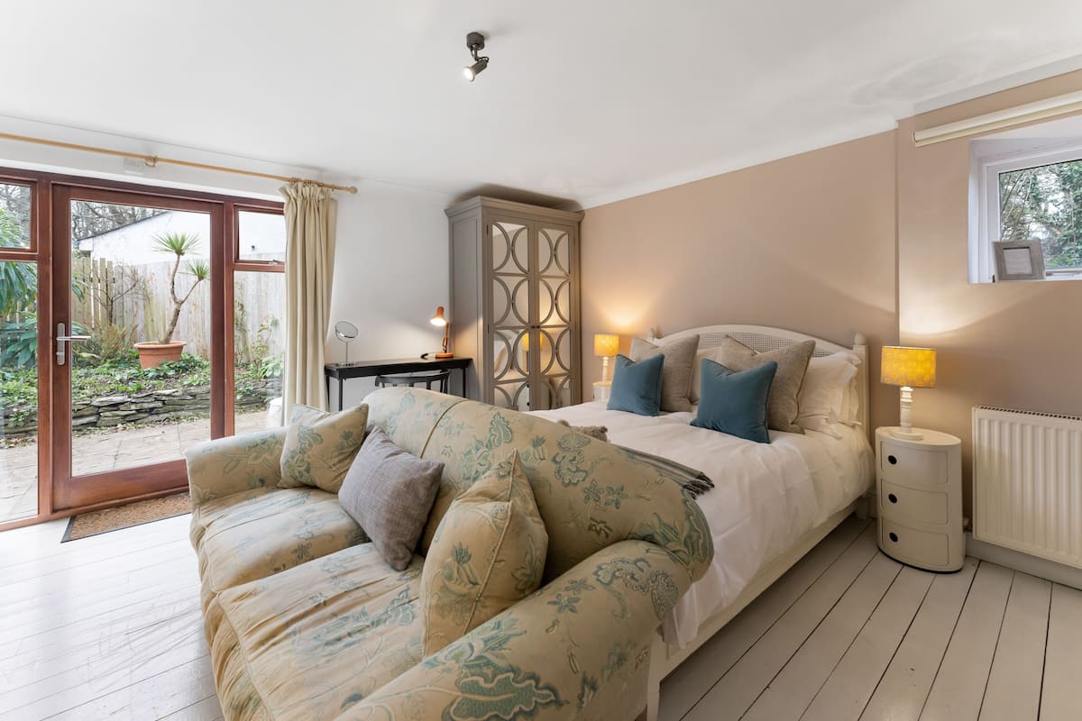 A bedroom with a bed, a sofa, a cabinet, and a window.