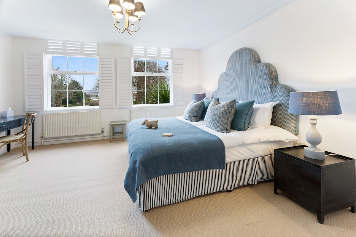 A bedroom with a bed, bedside tables, a chair, and a desk.