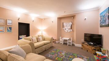 Relax in this inviting living room with a sofa, TV, and cozy play area.
