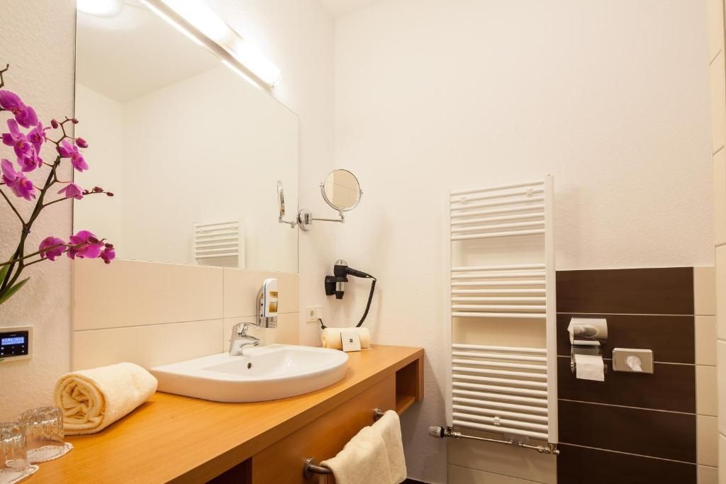 A bathroom with a white sink, a mirror, a towel, a hairdryer, and a towel rack.