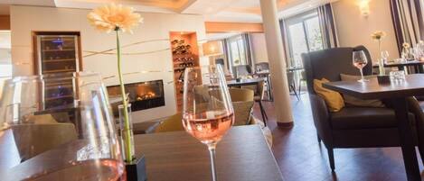 Un comedor con mesas, sillas y copas de vino.