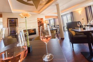 A dining area with tables, chairs, and wine glasses.