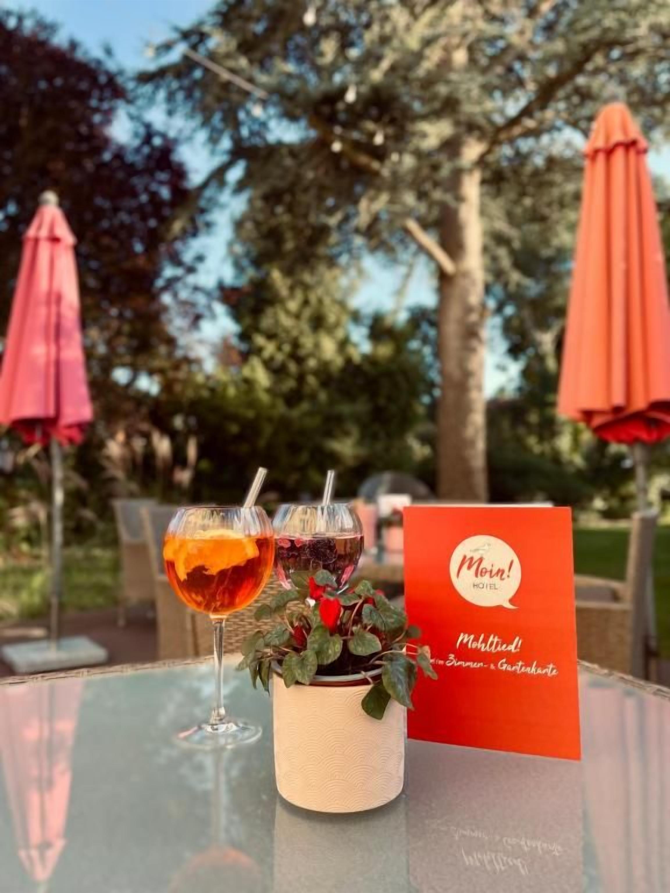 Una mesa de vidrio con dos bebidas y un cartel rojo con texto.