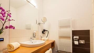 Un baño moderno con un lavabo redondo, un espejo, una toalla y un perchero para toallas.
